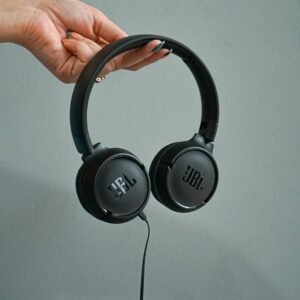A hand holding sleek JBL headphones, perfect for music lovers.